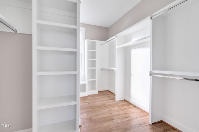 walk in closet with light hardwood / wood-style floors