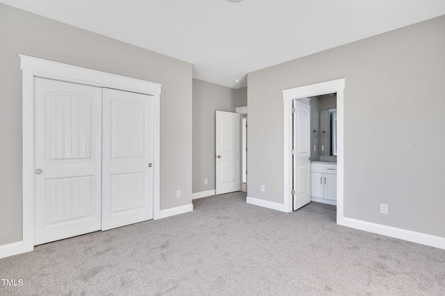 unfurnished bedroom with ensuite bathroom, light colored carpet, and a closet