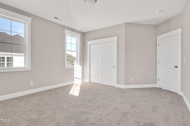 unfurnished bedroom with light colored carpet and a closet