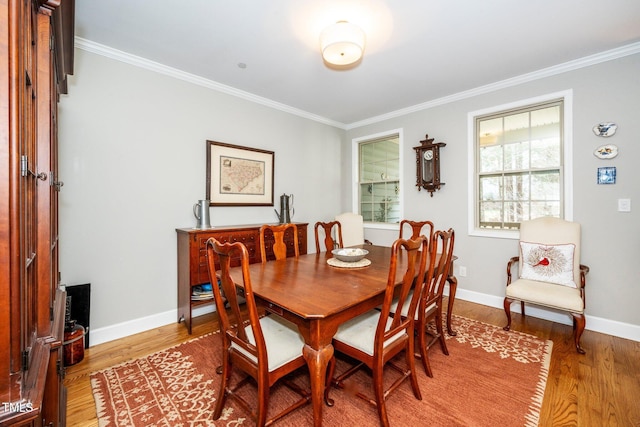 dining space featuring baseboards, wood finished floors, and crown molding