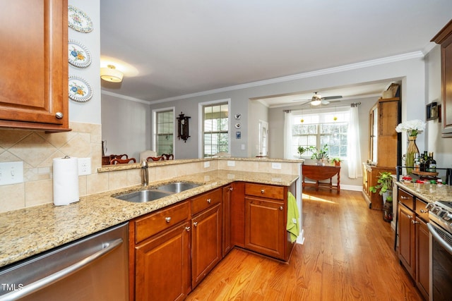 kitchen with a peninsula, light stone countertops, appliances with stainless steel finishes, and a sink