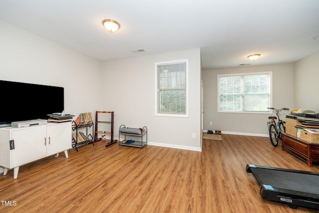 workout area featuring visible vents, light wood-style flooring, and baseboards