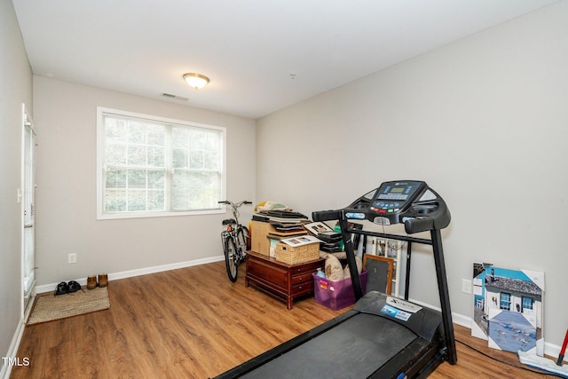 exercise area with wood finished floors, visible vents, and baseboards