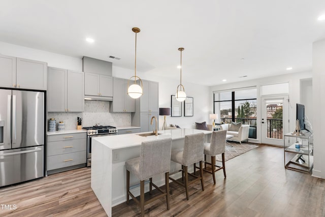 kitchen with sink, gray cabinetry, tasteful backsplash, an island with sink, and stainless steel appliances