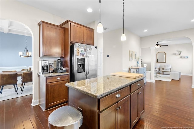 kitchen with light stone countertops, pendant lighting, dark hardwood / wood-style flooring, and stainless steel fridge with ice dispenser