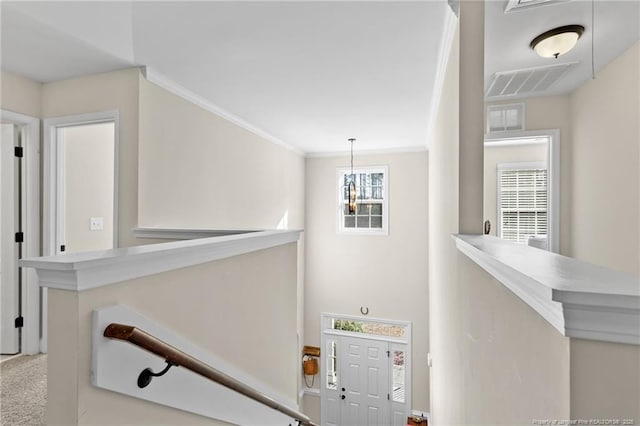 stairs featuring ornamental molding, plenty of natural light, carpet flooring, and a chandelier