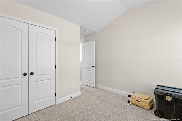 unfurnished bedroom featuring light colored carpet, vaulted ceiling, and a closet