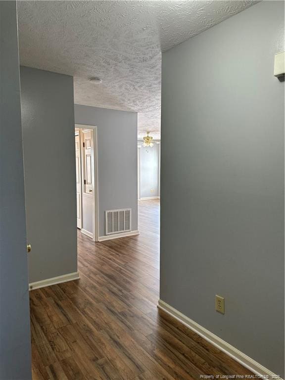 spare room with a textured ceiling, dark wood-type flooring, and ceiling fan