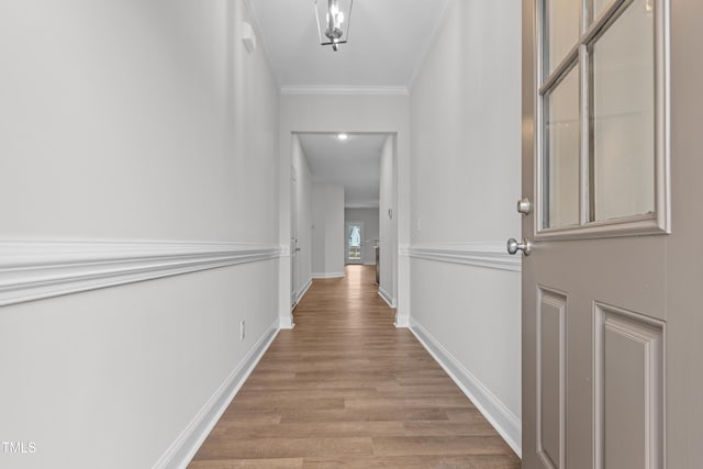 hall featuring crown molding, light wood-type flooring, and baseboards