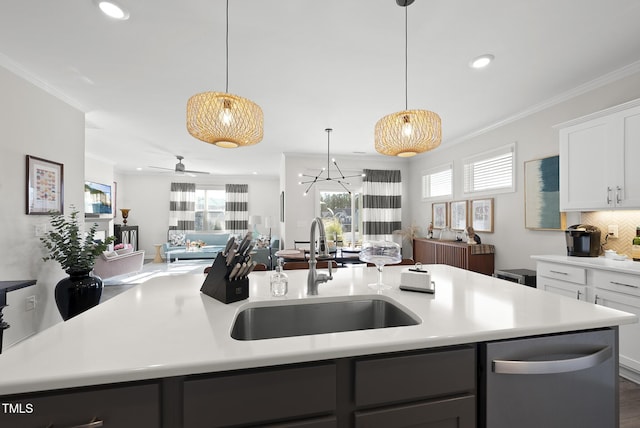 kitchen featuring pendant lighting, an island with sink, sink, white cabinets, and crown molding