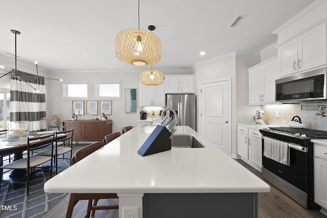 kitchen with stainless steel appliances, an island with sink, sink, and decorative light fixtures