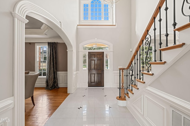 foyer entrance with crown molding and light tile patterned flooring