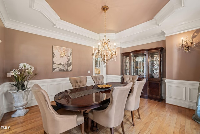 dining room with ornamental molding, a raised ceiling, light hardwood / wood-style floors, and a notable chandelier