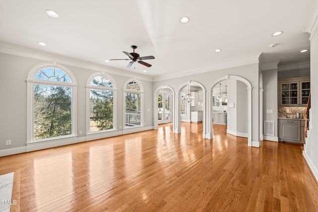 unfurnished living room featuring ornate columns, ornamental molding, ceiling fan, and light wood-type flooring