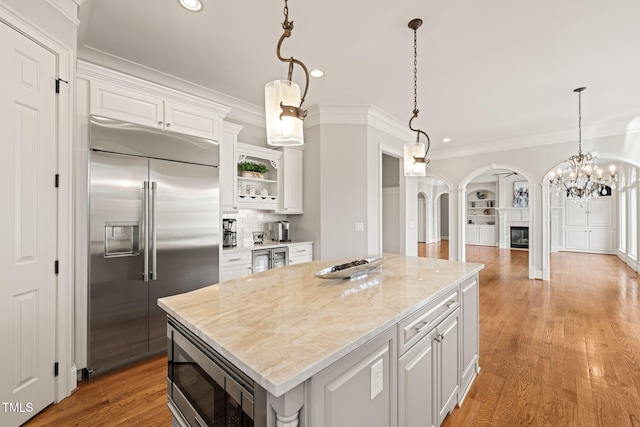 kitchen with built in appliances, white cabinetry, and a center island