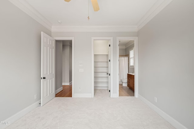 unfurnished bedroom with ornamental molding, a spacious closet, light colored carpet, ceiling fan, and a closet