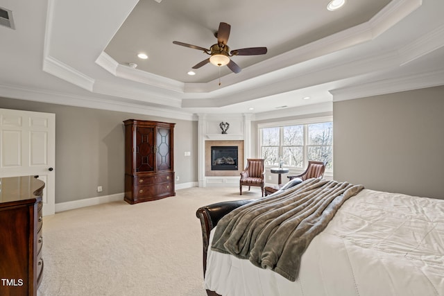 bedroom with light carpet, ornamental molding, a tile fireplace, and a raised ceiling