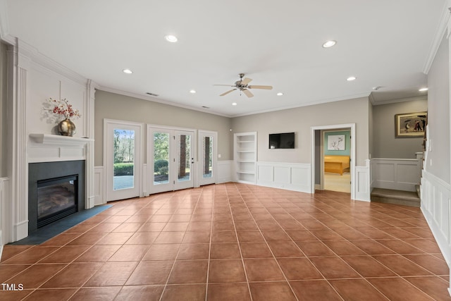 unfurnished living room with built in shelves, tile patterned floors, crown molding, ceiling fan, and a fireplace