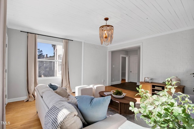 living room featuring crown molding, light hardwood / wood-style flooring, and brick wall