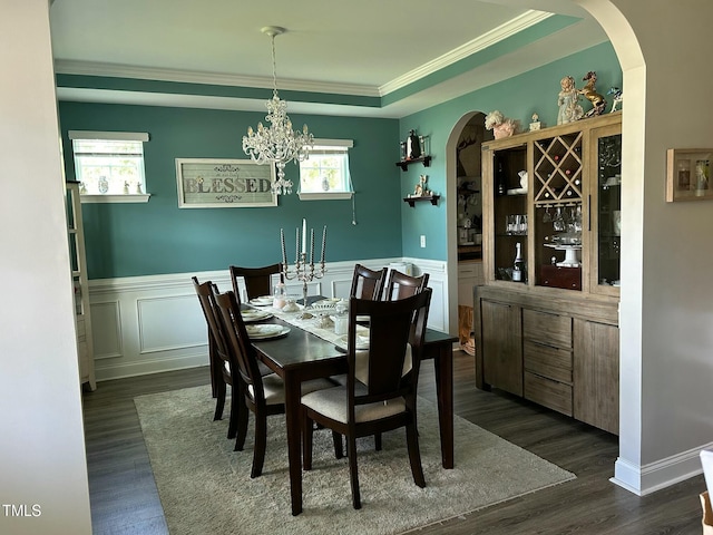 dining space featuring an inviting chandelier, ornamental molding, dark hardwood / wood-style flooring, and a raised ceiling