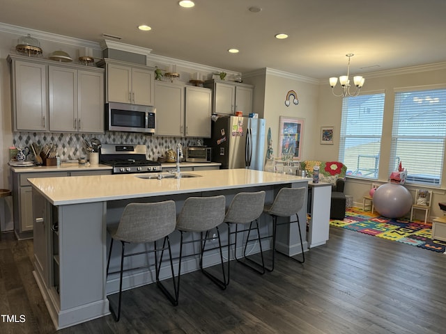 kitchen featuring stainless steel appliances, light countertops, a center island with sink, and gray cabinetry