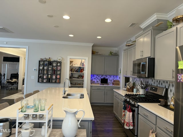 kitchen featuring a breakfast bar area, stainless steel appliances, gray cabinets, light countertops, and a sink