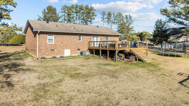 back of house with a wooden deck, a yard, crawl space, a trampoline, and brick siding