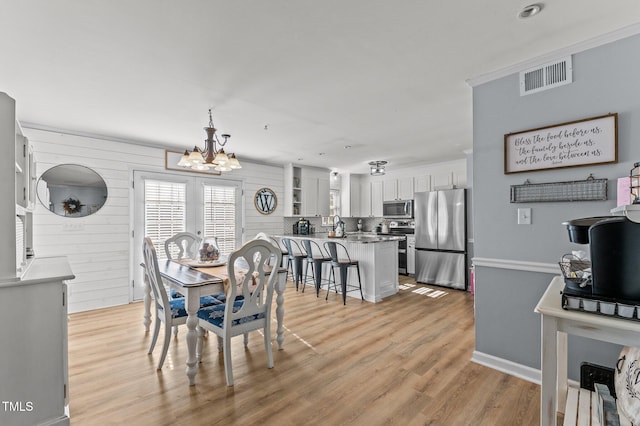 dining area with a chandelier, visible vents, and light wood finished floors