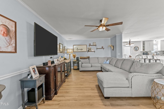 living area with light wood-style flooring, ceiling fan with notable chandelier, and ornamental molding