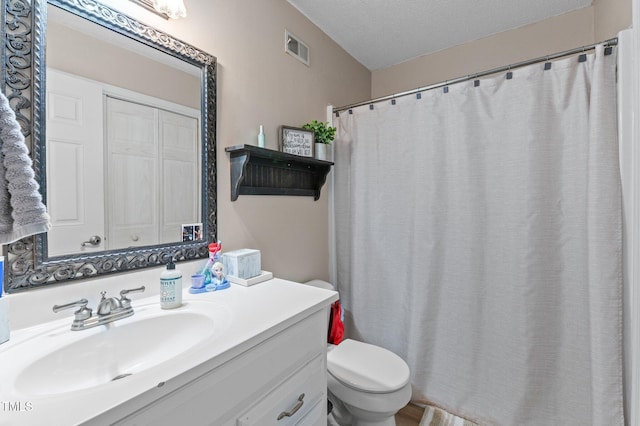 full bath featuring visible vents, toilet, vanity, and a textured ceiling