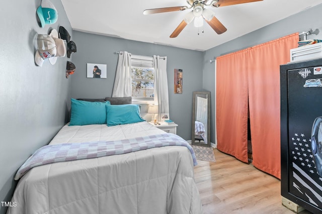 bedroom featuring ceiling fan, black refrigerator, and light wood-style floors