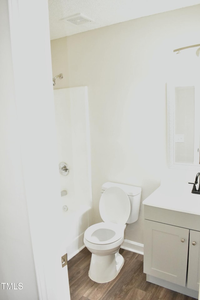 full bathroom featuring toilet, shower / bathing tub combination, a textured ceiling, vanity, and hardwood / wood-style floors