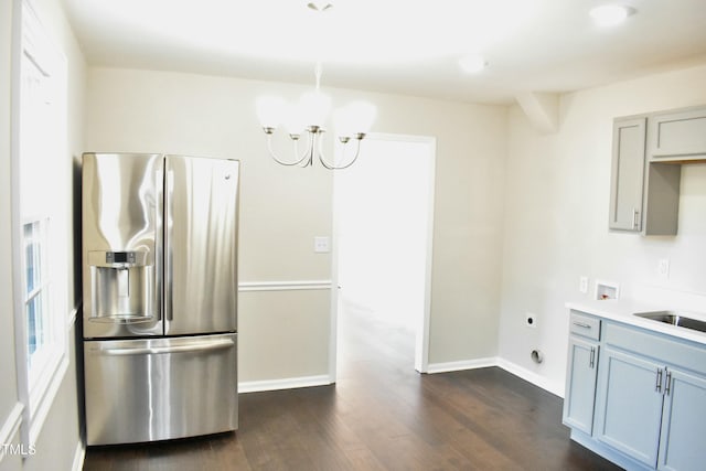 kitchen with dark wood-type flooring, sink, stainless steel fridge, and an inviting chandelier