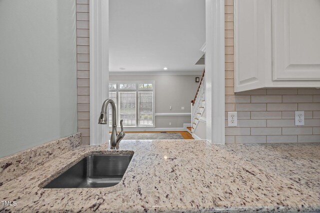 2035 Stuart Ct, Burlington, NC 27215 - kitchen view of a sink, crown molding, tasteful backsplash, light stone countertops, and white cabinetry
