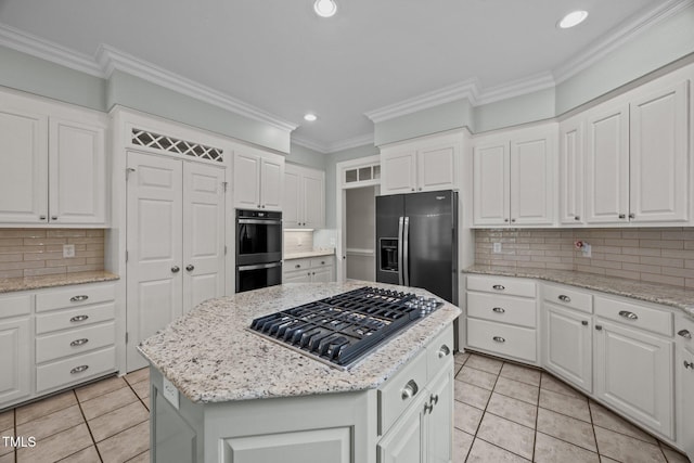 2035 Stuart Ct, Burlington, NC 27215 - kitchen with appliances with stainless steel finishes, light tile patterned floors, a kitchen island, backsplash, and ornamental molding