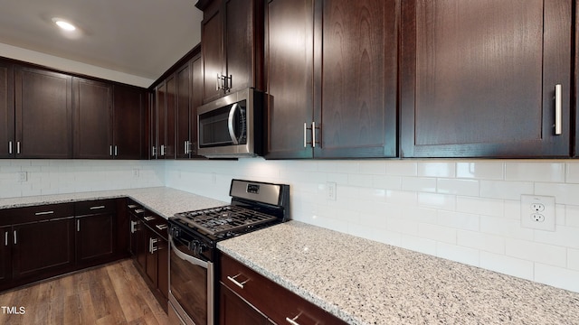 kitchen featuring stainless steel appliances, light stone countertops, dark hardwood / wood-style flooring, and decorative backsplash