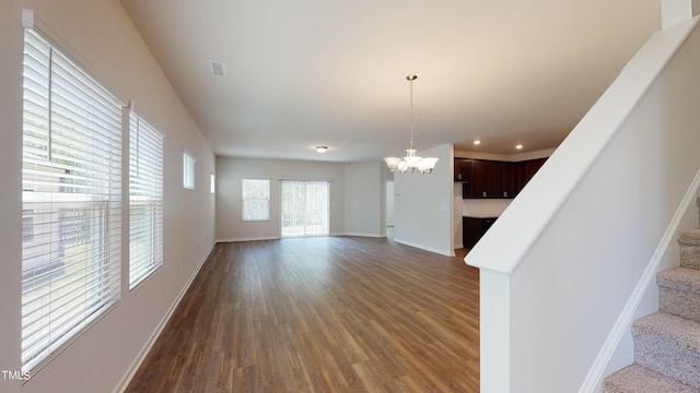 unfurnished living room featuring a notable chandelier and dark wood-type flooring