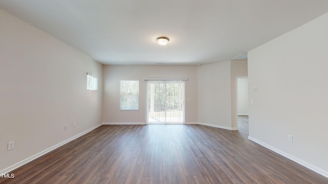 spare room with dark hardwood / wood-style flooring and a wealth of natural light