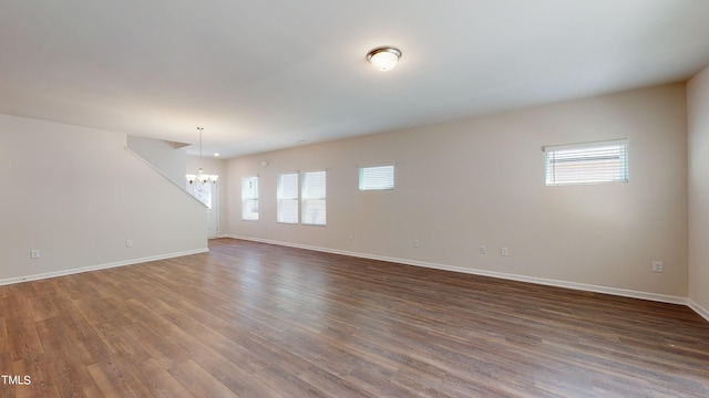 spare room featuring an inviting chandelier, dark hardwood / wood-style floors, and a healthy amount of sunlight