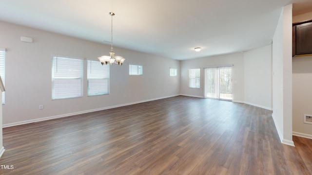 empty room featuring an inviting chandelier and dark hardwood / wood-style floors