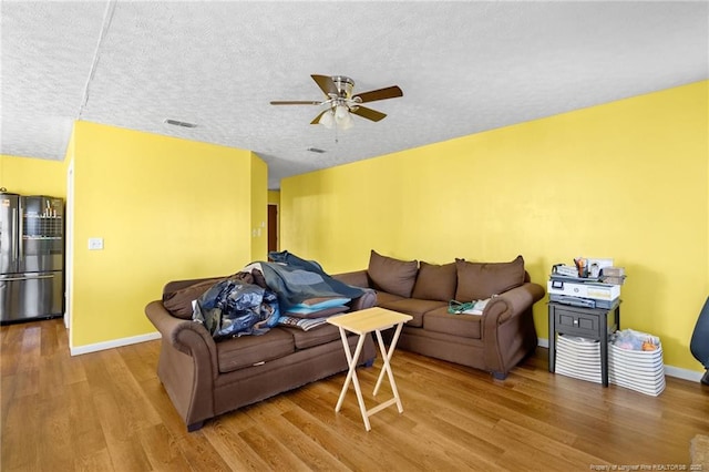 living room featuring hardwood / wood-style flooring, ceiling fan, and a textured ceiling