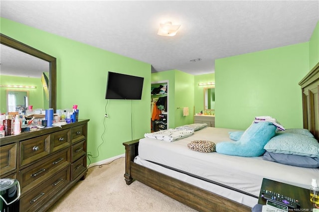 bedroom with connected bathroom, light carpet, and a textured ceiling