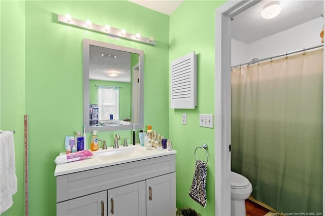 bathroom with vanity, curtained shower, a textured ceiling, and toilet