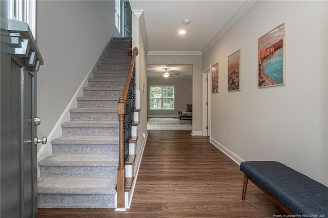 staircase with ornamental molding, hardwood / wood-style floors, and ceiling fan