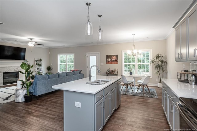 kitchen with gray cabinetry, sink, decorative light fixtures, and a center island with sink