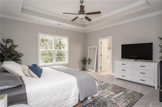 bedroom with ensuite bath, light carpet, ornamental molding, a tray ceiling, and ceiling fan