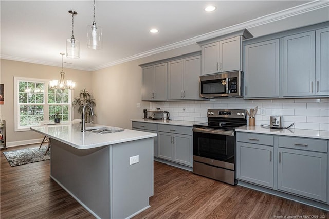 kitchen with gray cabinets, appliances with stainless steel finishes, decorative light fixtures, sink, and a kitchen island with sink