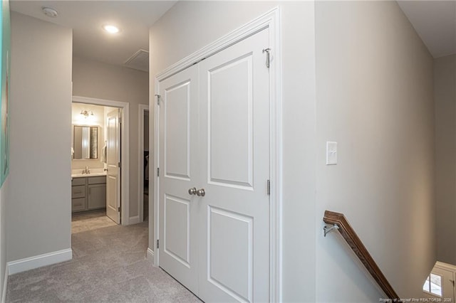 hallway featuring sink and light colored carpet