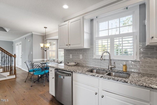 kitchen featuring pendant lighting, sink, crown molding, dishwasher, and white cabinets