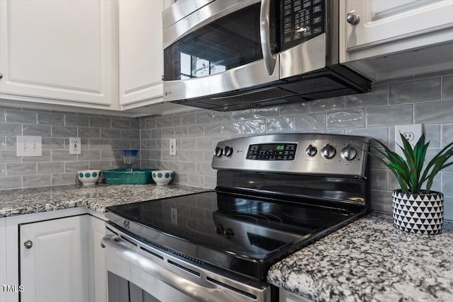 kitchen featuring white cabinetry, light stone counters, decorative backsplash, and appliances with stainless steel finishes